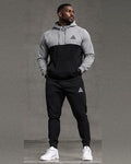 Male model wearing a GE grey and black colour-block pullover hoodie with black cuffed joggers, full-length front view.