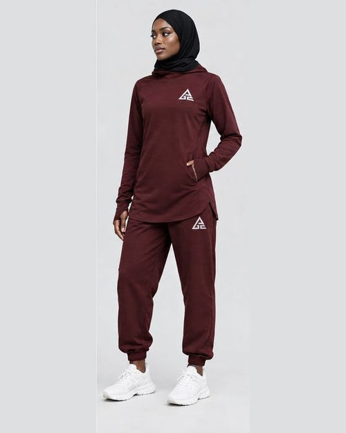 Female model wearing a burgundy GE longline top and matching cuffed joggers, styled with a black hijab and white trainers.