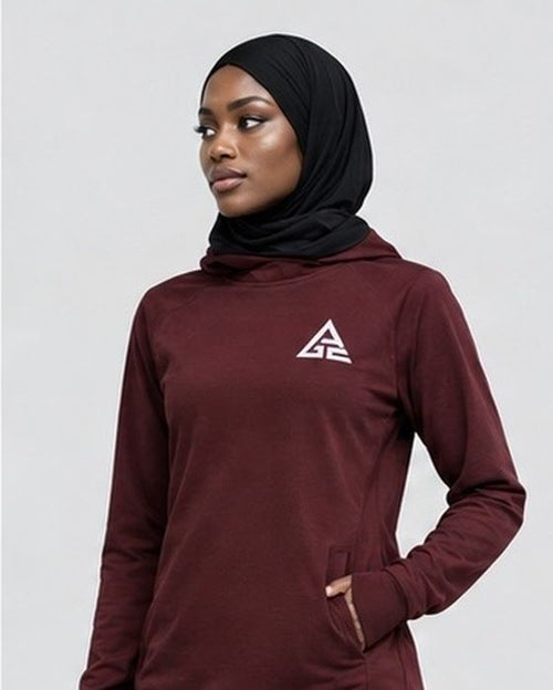 Close-up of the burgundy GE long-sleeve top showing the white chest logo and pocket detail, styled with a black hijab.