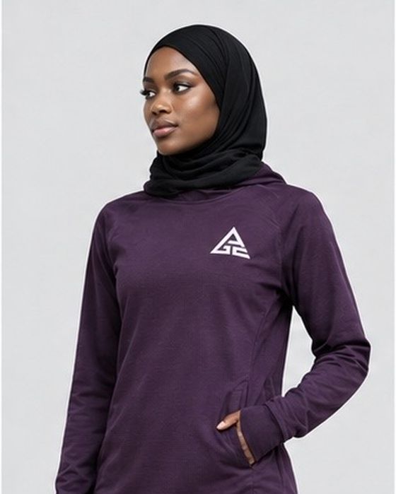 Close-up of the plum GE long-sleeve top showing the white chest logo and pocket detail, styled with a black hijab.