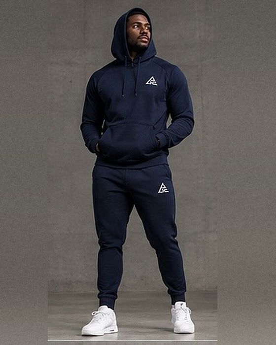 Male model wearing a navy blue GE pullover hoodie with front pouch pocket and matching cuffed joggers with white GE logos.