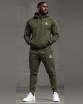 Male model wearing an olive green GE pullover hoodie with a front pouch pocket and matching cuffed joggers with white GE logos.